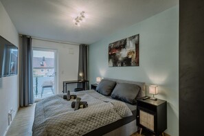 Das Schlafzimmer ebenfalls mit großem Doppelbett und Zugang zum Balkon. Außerdem ein Flatscreen.