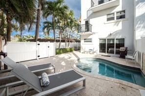 Relaxing poolside with palm trees and a townhome view.