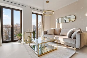 The modern and spacious living room with a couch, flatscreen TV, and dining area.