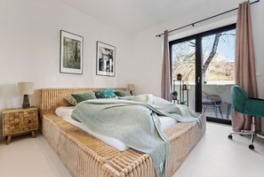 The bedroom with the large, cozy double bed and access to the balcony.