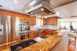 This chef’s kitchen boasts stainless steel appliances, granite countertops, and custom wood cabinetry—ideal for cooking and entertaining.