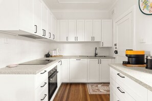 Prepare delicious meals in the beautifully renovated kitchen, featuring crisp white cabinetry, an oven, a Nespresso machine and stone benchtops.