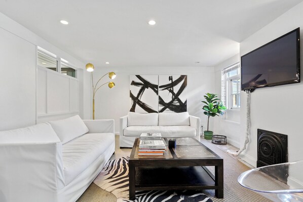 Relax in a large living room outfitted with a Smart TV and reading materials