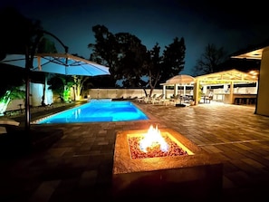 Enjoy a serene evening by the fire pit, with a glowing pool and ambient lighting