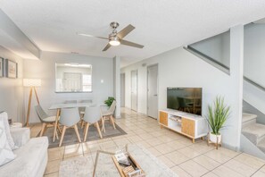 Modern open-concept living and dining area featuring a cozy seating space, a flat-screen TV, and a stylish dining setup for seamless comfort and entertainment.