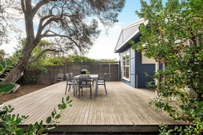 Outdoor patio with table, chairs, BBQ and outdoor shower.