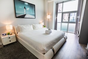 Bright and stylish bedroom with a king-sized bed, floor-to-ceiling windows, and modern decor for a cozy stay.