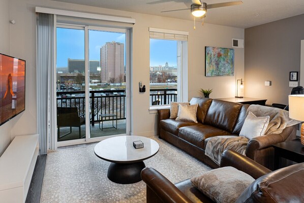 Beautifully designed living room. 65" TV, leather sofa and amazing views of mountains and city skyline.