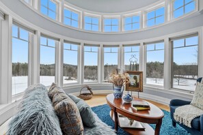 Nestle into this peaceful sitting area in the primary bedroom with panoramic views, ideal for savoring your morning coffee while nature's beauty unfolds outside.