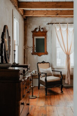 A cozy corner in the Hemingway Room, where vintage charm meets timeless comfort. Relax with a book or enjoy the natural light streaming through the large windows.