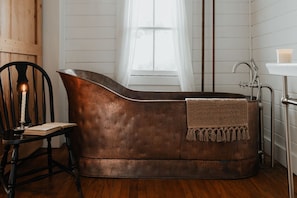 Romantic Candlelit Bath Experience – A freestanding vintage tub, flickering candlelight, and a well-placed book create the perfect atmosphere for a peaceful retreat.