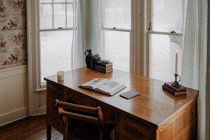 Serene Writing Nook with a View – A beautifully aged wooden desk positioned by large windows invites guests to write, read, or simply enjoy a quiet moment while gazing at the snow-dusted landscape outside.