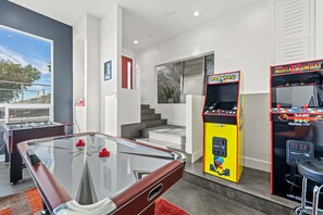 Ultimate Game Room Retreat with Classic Arcade Machines, Air Hockey, and Foosball – A Perfect Entertainment Space for Fun and Relaxation in a Stylish, Modern Setting with Sleek Design and Vibrant Ambiance.