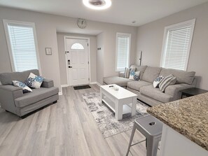 Open concept floor plan features living room with sofa, table and chair with bar