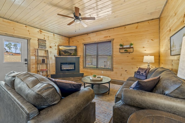 Unwind in the inviting living area, featuring a plush sofa and comfy chairs nestled by the warm glow of the electric fireplace—perfect for relaxing after a day of adventure.