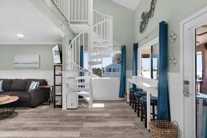 Living space flooded with natural light and spiral staircase leading to the upper level.