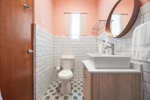 Modern bathroom, with mirror and cabinets, comfortable toilet . where classic design meets modern comfort. The soft peach walls create a warm and inviting ambiance, beautifully complemented by the crisp white subway tile and playful patterned floor.
