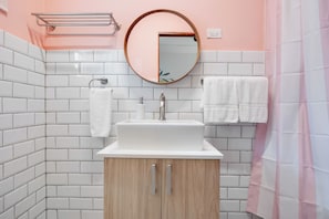 Modern bathroom, with mirror and cabinets, comfortable toilet . Hand towel, face towil and towel rack. Pink shower curtain.