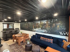 Basement seating area with game table, dry bar, mini fridge, custom mural