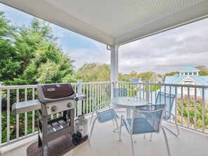 Covered balcony with a BBQ grill and outdoor seating—ideal for cookouts with a view.