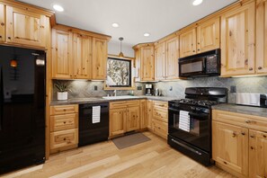 The kitchen boasts dark quartz countertops, sleek appliances, and a gas range