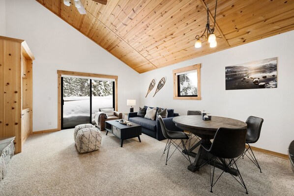 The spacious great room offers cozy seating, soft carpeting, and entrance to the deck