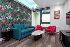 Open-plan living area with a sofa, TV, dining space, and a fully equipped kitchen