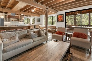 "Relax and gather in our inviting living space, where modern amenities meet rustic charm under exposed wooden beams.