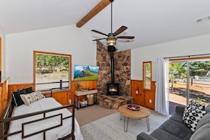 The cabin's living room has a wood burning stove, Smart TV, and board games.