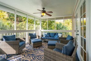Screened in porch with cozy seating area and dining table