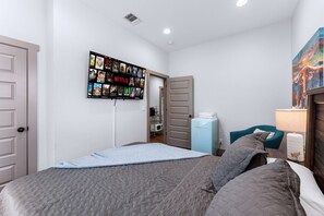 Queen sized bedroom with mini fridge and smart TV