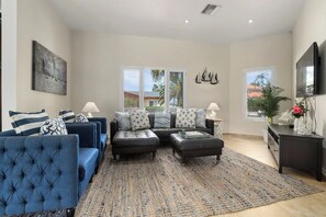 The modern and elegantly furnished living area features plush leather seating, a wall-mounted flat-screen TV, and an open layout—perfect for relaxing after a day of island adventures.