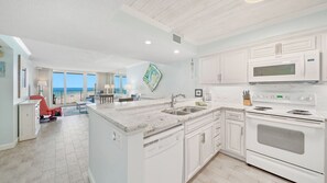 Fully equipped kitchen with view of dining area and living room.