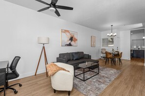 Modern living room with accent wall, dedicated working space, TV, plush couch, and sofa bed
