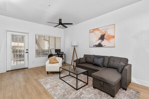 Modern living room with accent wall, dedicated working space, TV, plush couch, and sofa bed