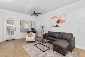 Modern living room with accent wall, dedicated working space, TV, plush couch, and sofa bed