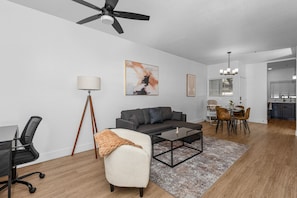 Modern living room with accent wall, dedicated working space, TV, plush couch, and sofa bed