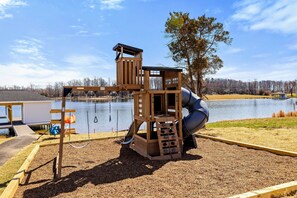 Children's Play Area: Delightful lakeside playset offering hours of fun, safely designed with slides, swings, and climbing features, all with picturesque lake views.