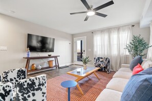 Stylish open-concept living room with bold chairs, plush sofa, and mirror.
