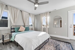Sunlit bedroom with a queen bed, private balcony, cozy nook, and serene vibes.
