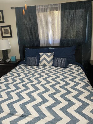 Bedroom with queen-size bed, lamps and clothes hamper