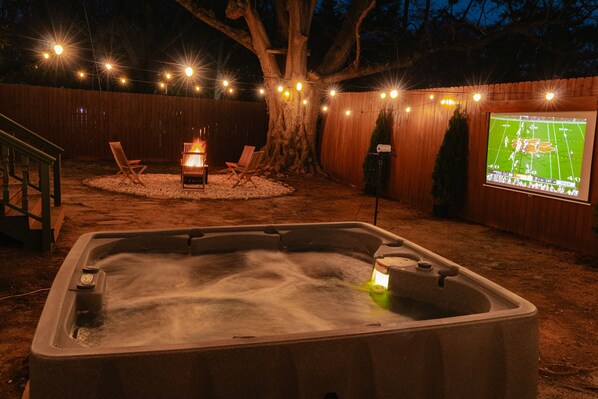 Unwind in the hot tub, enjoying the peaceful backyard and serene outdoor atmosphere.