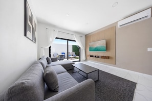 Chill vibes in this cozy living room, where a sleek sofa invites you to relax while enjoying the view of the outdoor space through the large glass doors.