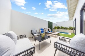 Stylish outdoor seating area designed for comfort and relaxation, featuring cozy chairs and loungers, with a glimpse of the inviting plunge pool in the background.