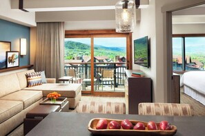 Spacious living room features a sleeper sofa and a door to a private, furnished patio/balcony.