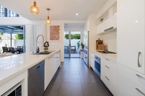 The fully equipped kitchen boasts stone benchtops, quality stainless steel appliances, and a large island—perfect for preparing family meals or casual snacks.