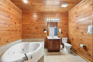 Unwind in the oversized jetted tub surrounded by warm wood paneling and a well-lit vanity—your private mountain spa experience.