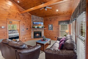 Cozy up in the inviting living room featuring a stone fireplace, Smart TV, and plush leather seating—the perfect place to unwind after a day in the mountains.