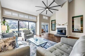 - Elegant living room with soaring ceilings, designer mirrors, and modern fireplace
- Wall of windows opens to golf course views and lets natural light pour in
- Plush leather seating surrounds a glass coffee table in the serene layout