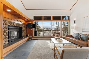 Living area featuring ample seating, flat-screen TV, wood burning fireplace, and balcony access.